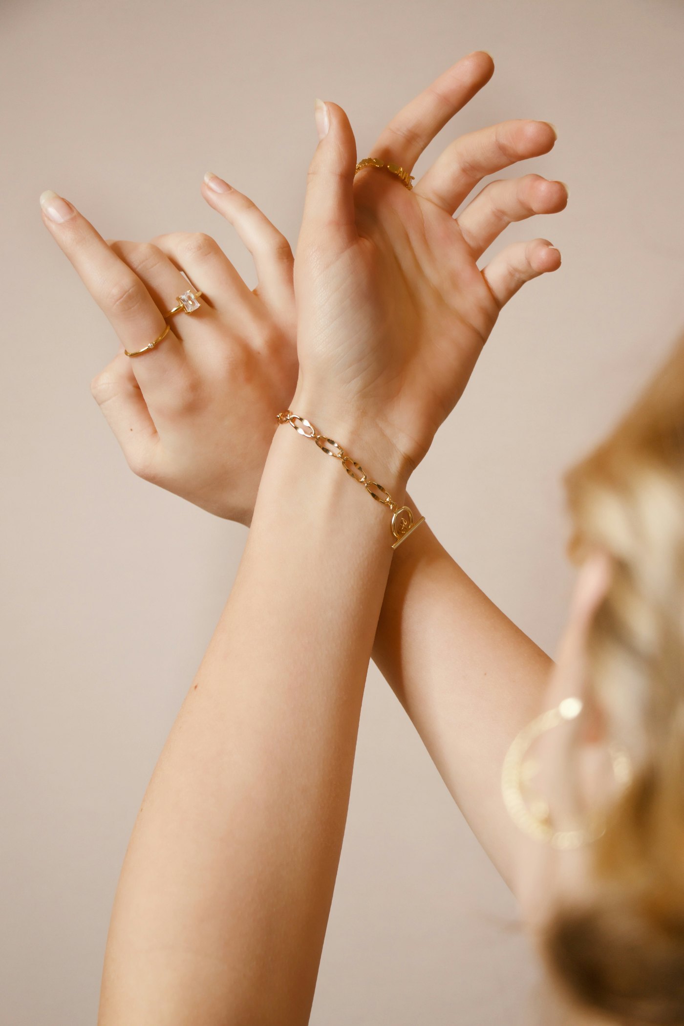 Hands raised with fine gold bracelets on the wrists