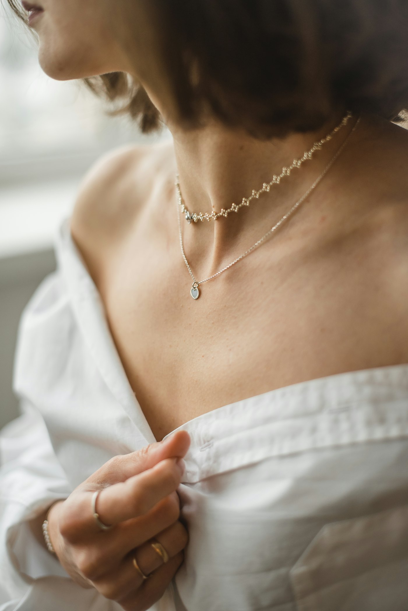 A fine necklace worn with an off-the-shoulder white top