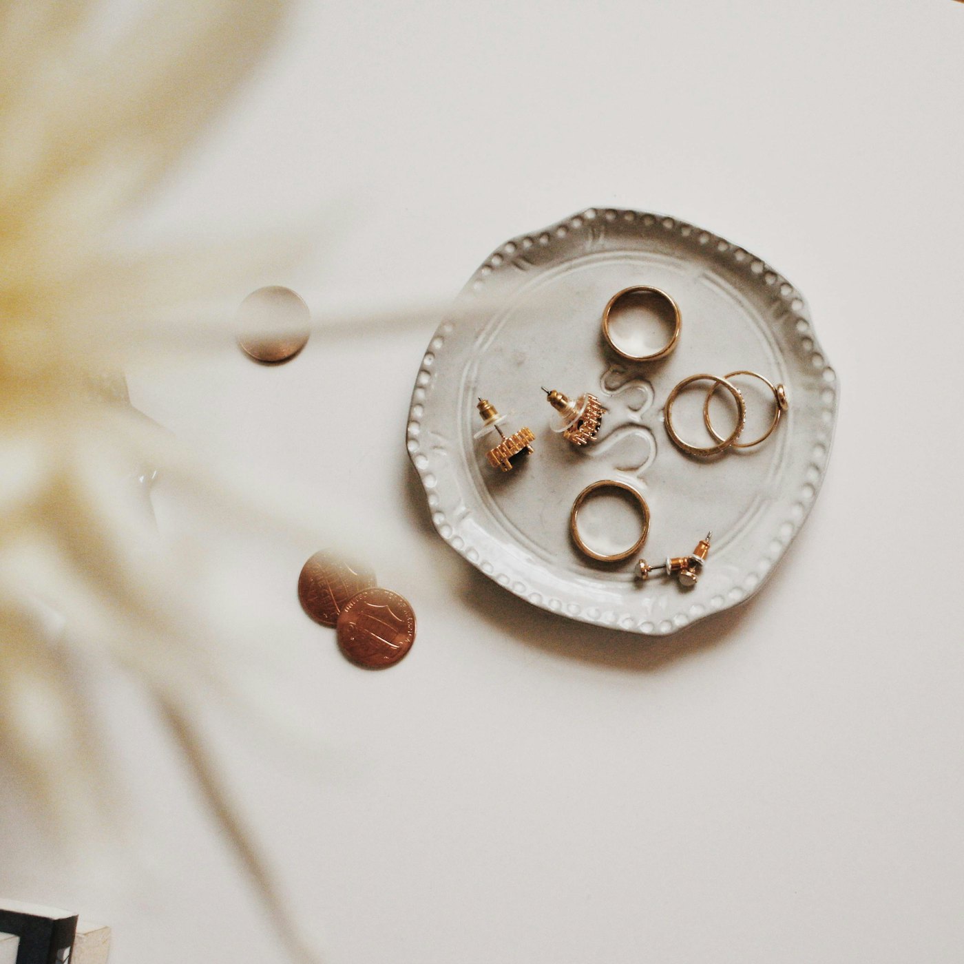 A small ceramic dish holding handmade studs and rings in soft daylight